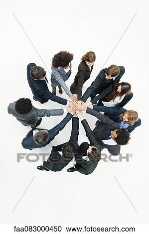 Stock Image - Business associates standing in circle with hands clasped in motivational exercise. Fotosearch