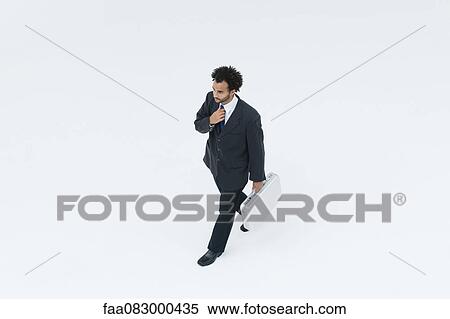 Stock Photography - Businessman adjusting tie while on the move. Fotosearch