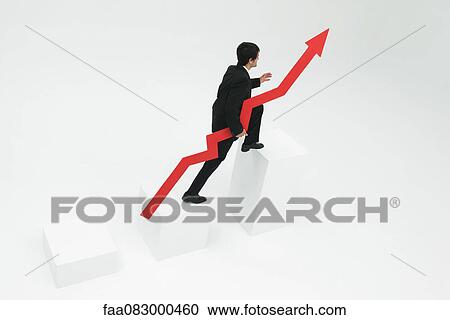 Stock Image - Businessman ascending steps holding arrow pointed upward. Fotosearch