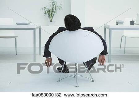 Businessman napping in chair in office, rear view View Large Photo Image Stock Image - Businessman napping in chair in office, rear view. Fotosearch