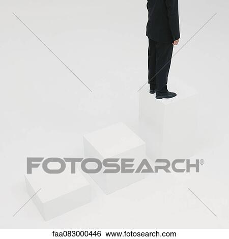 Stock Photograph - Businessman standing on highest step, cropped. Fotosearch