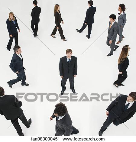 Businessman standing still in midst of other business professionals on the move View Large Photo Image Stock Image - Businessman standing still in midst of other business professionals on the move. Fotosearch