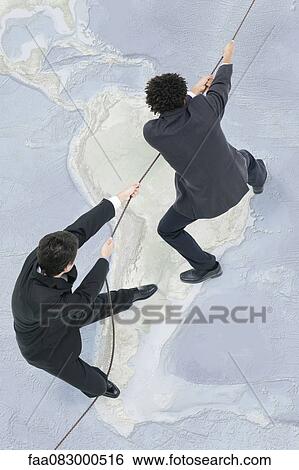 Businessmen standing on top of world map, pulling rope View Large Photo Image Stock Photograph - Businessmen standing on top of world map, pulling rope. Fotosearch