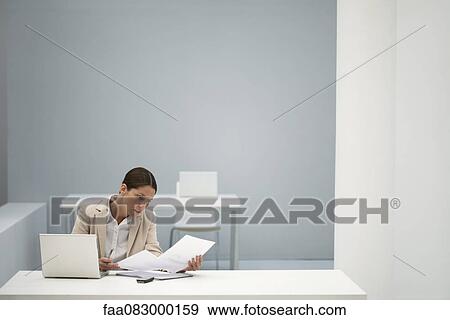 Stock Photo - Businesswoman reading documents in office. Fotosearch
