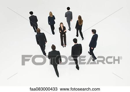 Stock Image - Businesswoman standing in midst of other anonymously dressed business professionals. Fotosearch