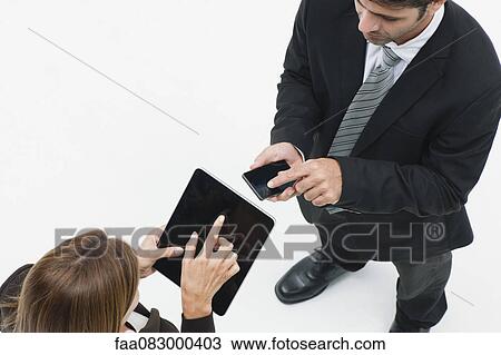 Businesswoman using digital tablet, businessman using smartphone View Large Photo Image Stock Image - Businesswoman using digital tablet, businessman using smartphone. Fotosearch