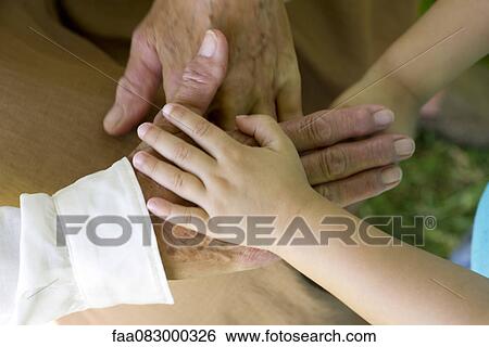 Stock Photograph - Child's hand holding elderly person's hand. Fotosearch