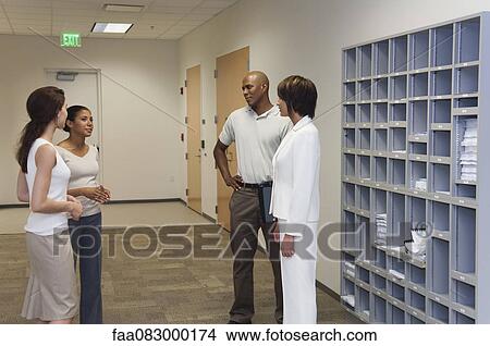 Colleagues chatting in office corridor View Large Photo Image Picture - Colleagues chatting in office corridor. Fotosearch