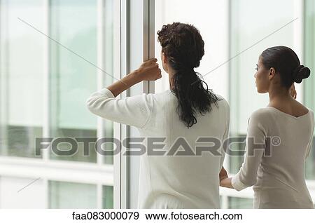 Colleagues standing side by side looking out of window, rear view View Large Photo Image Stock Photo - Colleagues standing side by side looking out of window, rear view. Fotosearch