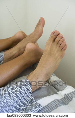 Couple relaxing in bed, low section View Large Photo Image Stock Image - Couple relaxing in bed, low section. Fotosearch