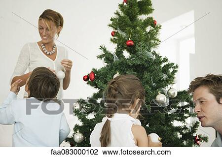 Family decorating Christmas tree together View Large Photo Image Stock Image - Family decorating Christmas tree together. Fotosearch