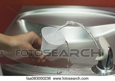 Stock Photograph - Filling cup at drinking fountain, cropped. Fotosearch