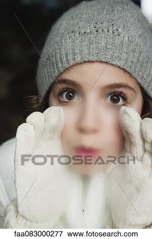Stock Photo - Girl breathing on window, dressed in winter clothes. Fotosearch
