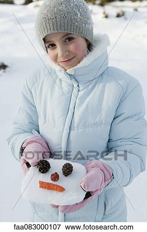 Stock Photo - Girl holding snowman face, portrait. Fotosearch