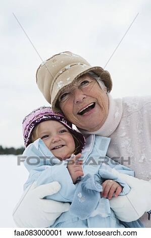 Stock Image - Grandmother and toddler girl embracing in snow. Fotosearch