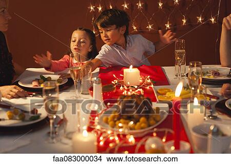 Picture - Little boy and little girl playing during Christmas dinner. Fotosearch