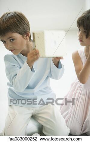 Little boy shaking gift box curiously View Large Photo Image Stock Image - Little boy shaking gift box curiously. Fotosearch
