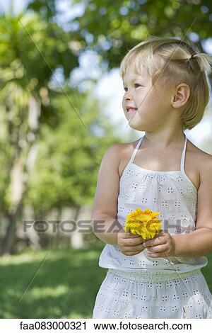 Little girl holding flower outdoors View Large Photo Image Stock Image - Little girl holding flower outdoors. Fotosearch