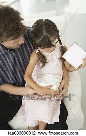 Little girl sitting on father's laps opening present View Large Photo Image Stock Image - Little girl sitting on father's laps opening present. Fotosearch