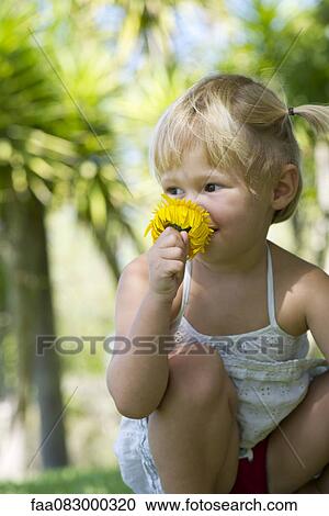 Stock Image - Little girl smelling flower. Fotosearch