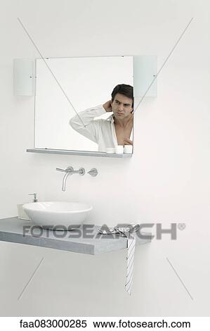 Man looking at self in bathroom mirror View Large Photo Image Stock Photography - Man looking at self in bathroom mirror. Fotosearch