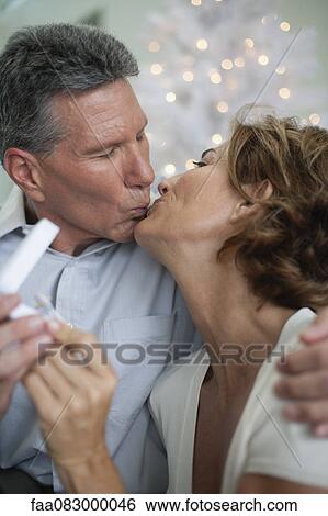 Stock Photograph - Mature couple kissing, man giving woman gift. Fotosearch