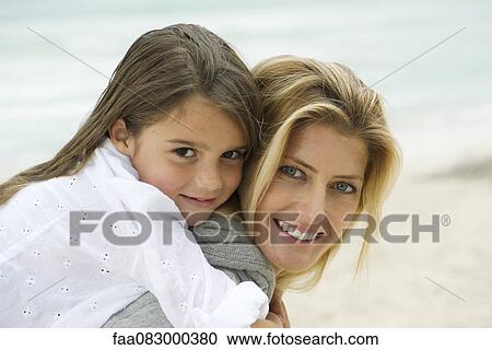Stock Image - Mother and daughter embracing at the beach, portrait. Fotosearch