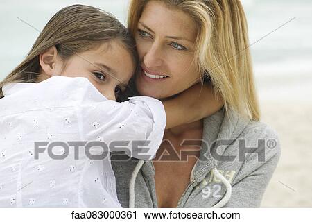 Stock Image - Mother and young daughter embracing outdoors. Fotosearch