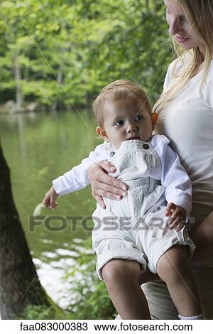 Mother carrying baby girl at water's edge View Large Photo Image Stock Image - Mother carrying baby girl at water's edge. Fotosearch