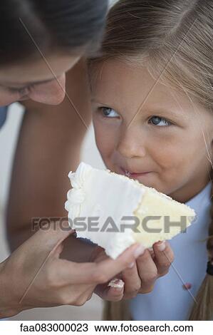 Mother feeding slice of cake to little girl View Large Photo Image Stock Image - Mother feeding slice of cake to little girl. Fotosearch