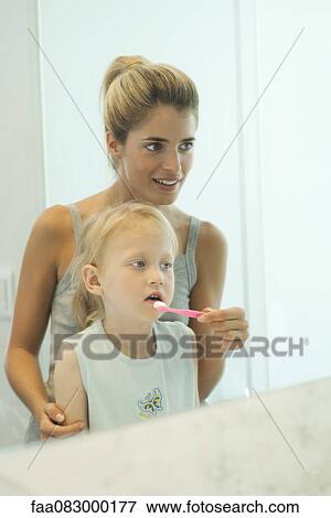Mother helping daughter brush her teeth View Large Photo Image Stock Photo - Mother helping daughter brush her teeth. Fotosearch