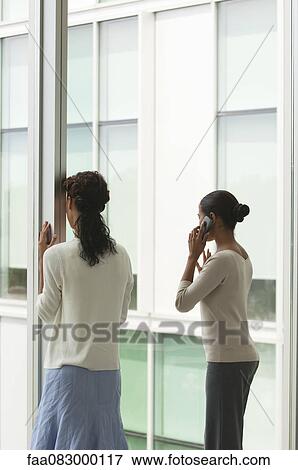 Office workers standing by window, one woman talking on cell phone, rear view View Large Photo Image Stock Photo - Office workers standing by window, one woman talking on cell phone, rear view. Fotosearch