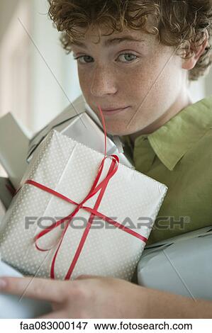 Preteen boy holding pile of presents View Large Photo Image Stock Photo - Preteen boy holding pile of presents. Fotosearch
