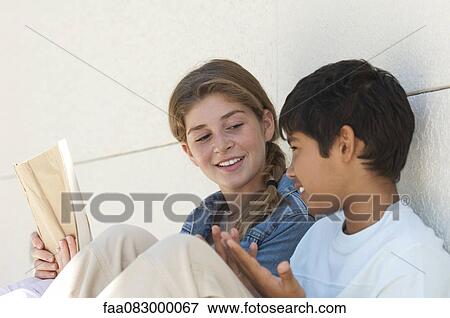 Preteen girl and boy sitting together outdoors View Large Photo Image Stock Photo - Preteen girl and boy sitting together outdoors. Fotosearch