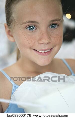Stock Photograph - Preteen girl unwrapping present, cropped. Fotosearch