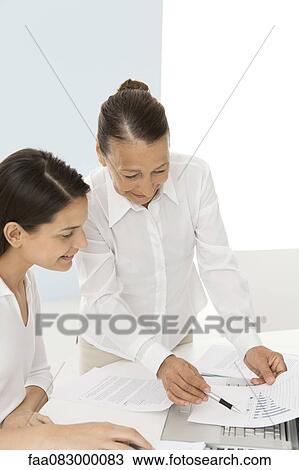 Senior woman assisting young female colleague with work View Large Photo Image Stock Image - Senior woman assisting young female colleague with work. Fotosearch