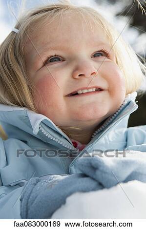 Stock Photo - Smiling toddler girl wearing winter clothes outdoors, portrait. Fotosearch