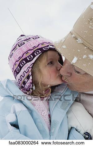 Picture - Toddler girl kissing grandmother in snow. Fotosearch