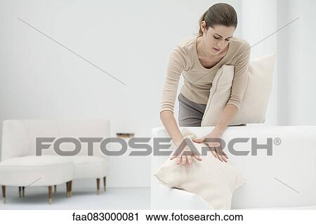 Woman arranging pillows on sofa View Large Photo Image Stock Image - Woman arranging pillows on sofa. Fotosearch
