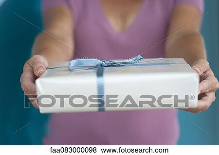 Stock Photo - Woman holding out present, mid section. Fotosearch