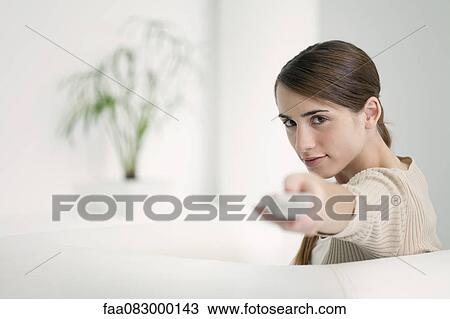 Stock Image - Woman holding out remote control. Fotosearch
