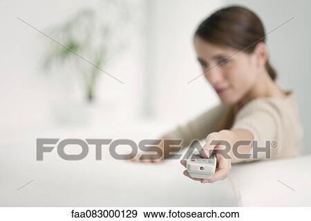 Stock Photo - Woman holding out remote control. Fotosearch
