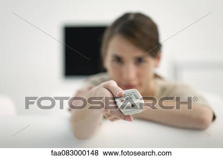 Stock Photo - Woman holding out remote control. Fotosearch