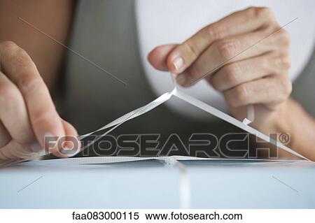Stock Photography - Woman tying ribbon on present. Fotosearch