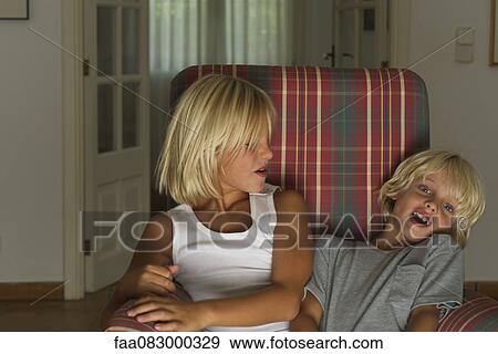 Stock Photo - Young brothers sitting together in armchair. Fotosearch
