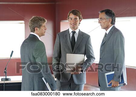 Stock Image - Young businessman talking with colleagues in office. Fotosearch