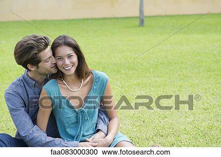 Stock Image - Young man kissing girlfriend on cheek. Fotosearch