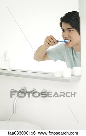 Young man looking in mirror, brushing teeth View Large Photo Image Stock Photograph - Young man looking in mirror, brushing teeth. Fotosearch
