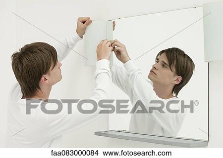 Picture - Young man repairing wall light in bathroom. Fotosearch