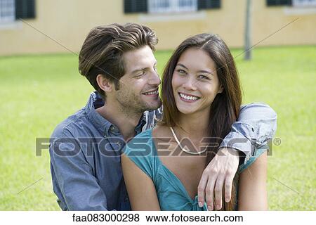Stock Photo - Young man with arm around girlfriend, portrait. Fotosearch